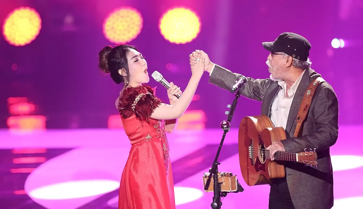 Penampilan dibuka dengan Iwan Fals yang menyanyikan lagu di bagian awal seorang diri, dan tak lama kemudian datang ke atas panggung Via Vallen dengan gaun merahnya yang menjuntai. (Bambang E.Ros/Bintang.com)
