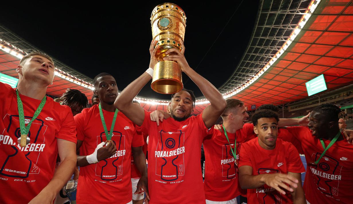 Pemain Leipzig, Christoper Nkunku (tengah) merayakan kemenangan dengan mengangkat trofi DFB Pokal atau Piala Liga Jerman bersama rekan setimnya usai mengalahkan SC Freiburg pada partai final yang berlangsung di Stadion Olimpiade di Berlin, Jerman, Sabtu, 21 Mei 2022 waktu setempat. Die Bullen berhasil menang lewat babak adu penalti dengan skor 4-2 usai laga berjalan imbang 1-1. (AFP/Ronny Hartmann)