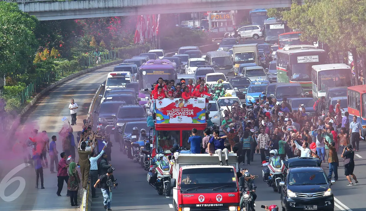 Warga antusias melihat arak-arakan para penyumbang medali Indonesia di Olimpiade Rio 2016 saat melintas menuju Istana Negara, Jakarta, Rabu (24/8). Rombongan para peraih medali ini memulai arak-arakan dari Gedung Kemenpora. (Liputan6.com/Angga Yuniar)