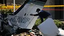 Petugas investigasi mengamati reruntuhan pesawat kecil yang jatuh ke area parkir sebuah pusat perbelanjaan di Santa Ana, California, Senin (6/8). Otoritas Penerbangan Federal AS (FAA) sedang menyelidiki insiden ini. (AP/Jae C. Hong)