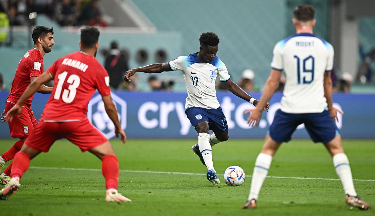 Bukayo Saka. Gelandang serang Arsenal berusia 21 tahun ini total mencetak 3 gol dan 1 assist dari 4 laga bagi Timnas Inggris pada ajang Piala Dunia 2022 yang menjadi Piala Dunia pertamanya. Dua dari tiga golnya dicetak ke gawang Iran pada laga pembuka Grup B yang berkesudahan 6-2 untuk kemenangan Three Lions. (AFP/Paul Ellis)