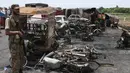 Petugas keamanan Pakistan berjaga di dekat bangkai kendaraan yang terbakar akibat ledakan truk tangki minyak di jalan raya dekat Bahawalpur, Pakistan (25/6). (AP Photo / Iram Asim)