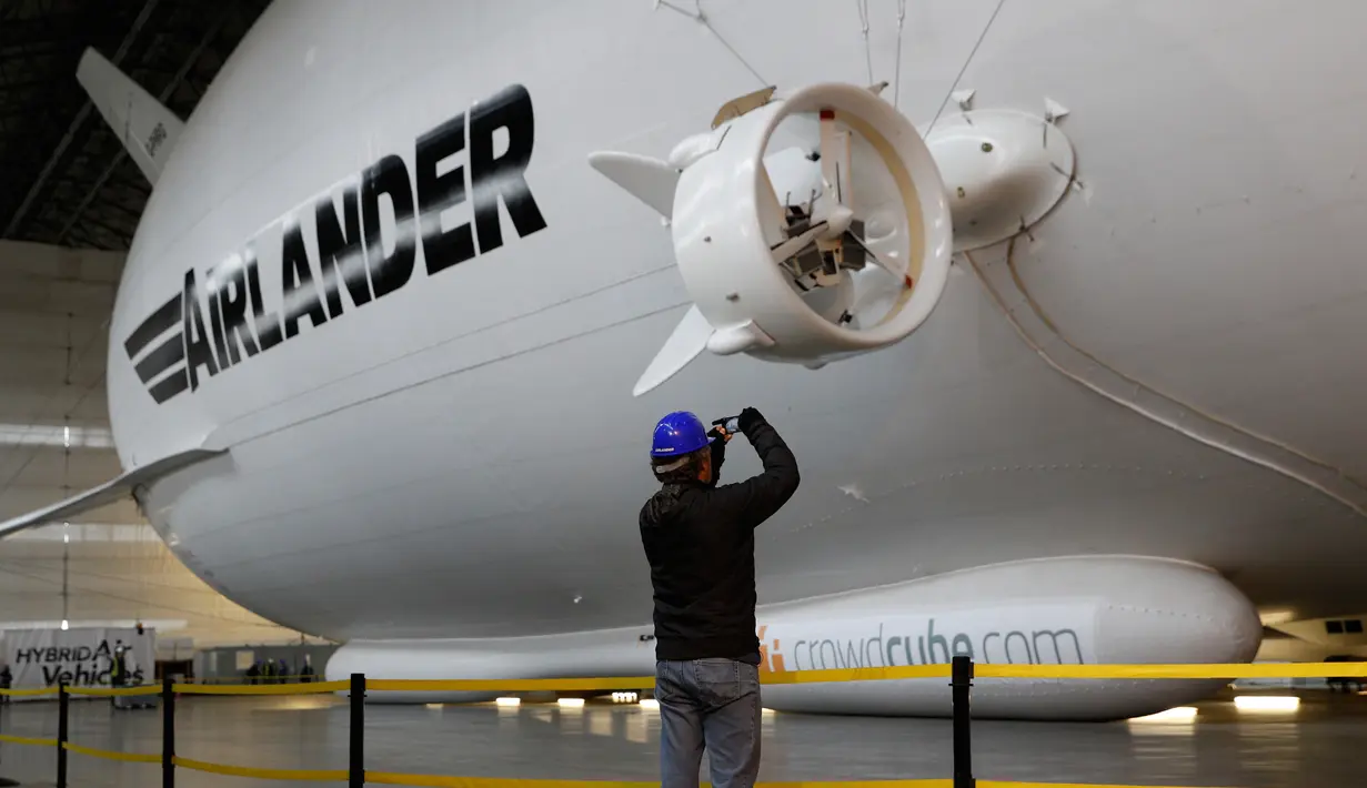 Pengunjung mengambil gambar dari The Airlander 10 saat peluncuran media di Cardington Airfield, Bedfordshire, Senin (21/3). Airlander 10 adalah pesawat hybrid, atau gabungan dari pesawat jet dan zeppelin yang dikenal mirip balon udara (ADRIAN DENNIS/AFP)