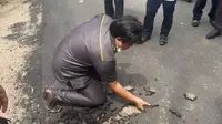 Anggota DPRD Muara Enim Sumatera Selatan (Sumsel) Yusran Effendi mengeruk aspal jalan yang sudah kering menggunakan tangan kosong (Dok. Instagram Muara Enim Terkini / Nefri Inge)