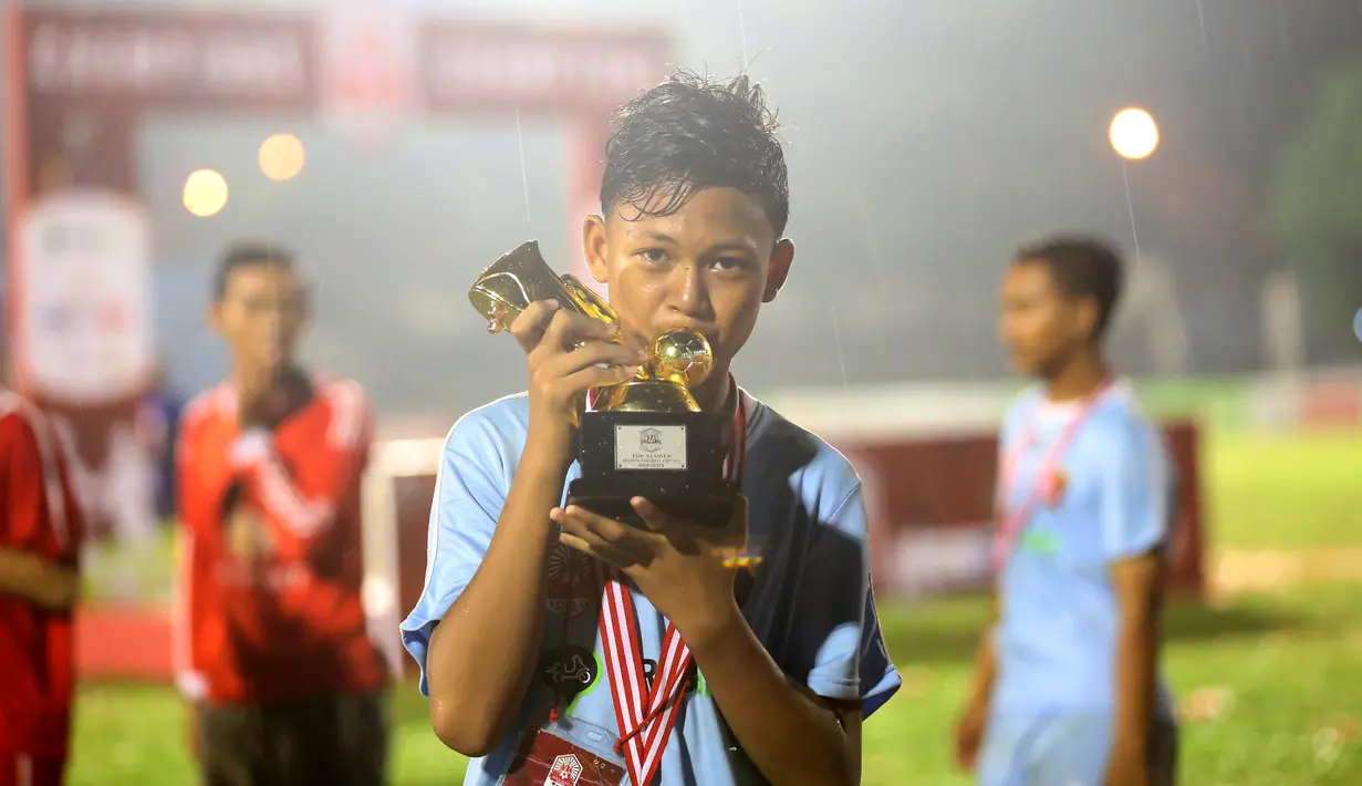 Pemain Terbaik Rusun Cup 2015 dari Rusun Daan Mogot, Mohammad Sobri, berpose dengan pialanya seusai laga final di Stadion Soemantri Brojonegoro, Jakarta, Minggu (8/11/2015). ( Bola.com/Nicklas Hanoatubun)