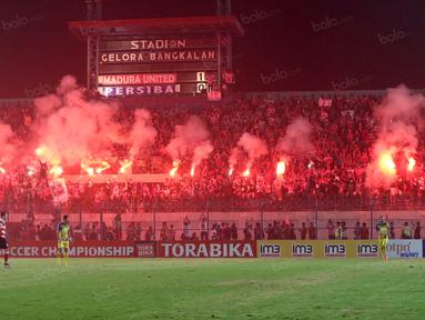 Suporter Madura United, menyalakan flare memperingati ulang tahunnya membuat laga melawan Persiba Balikpapan tertunda pada Torabika SC 2016 di Stadion Gelora Bangkalan, Senin(13/6/2016).  (Bola.com/Nicklas Hanoatubun)