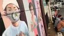 Warga duduk di dekat mural bergambar simbol orang berdoa menggunakan masker di kawasan Juanda, Kota Depok, Jumat (26/6/2020). Mural yang dibuat warga itu bertujuan memberi edukasi untuk menggunakan masker sebagai salah satu pencegahan dan penyebaran COVID-19. (Liputan6.com/Immanuel Antonius)