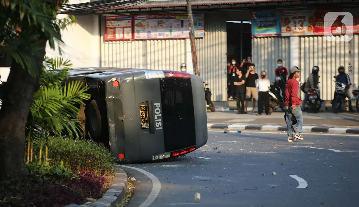 Sebuah mobil polisi dirusak massa saat bentrok di kawasan Pejompongan, Jakarta, Rabu (7/10/2020). (Liputan6.com/Faizal Fanani)