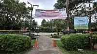 Spanduk terpasang di taman saat pemberlakuan karantina wilayah skala kecil atau mini lockdown di RT 011 RW 009, Kelurahan Kayu Putih, Pulogadung, Jakarta Timur, Minggu (6/6/2021). Sebanyak 14 warga positif COVID-19 saat ini telah dibawa ke RSD Wisma Atlet Kemayoran. (merdeka.com/Iqbal S. Nugroho)