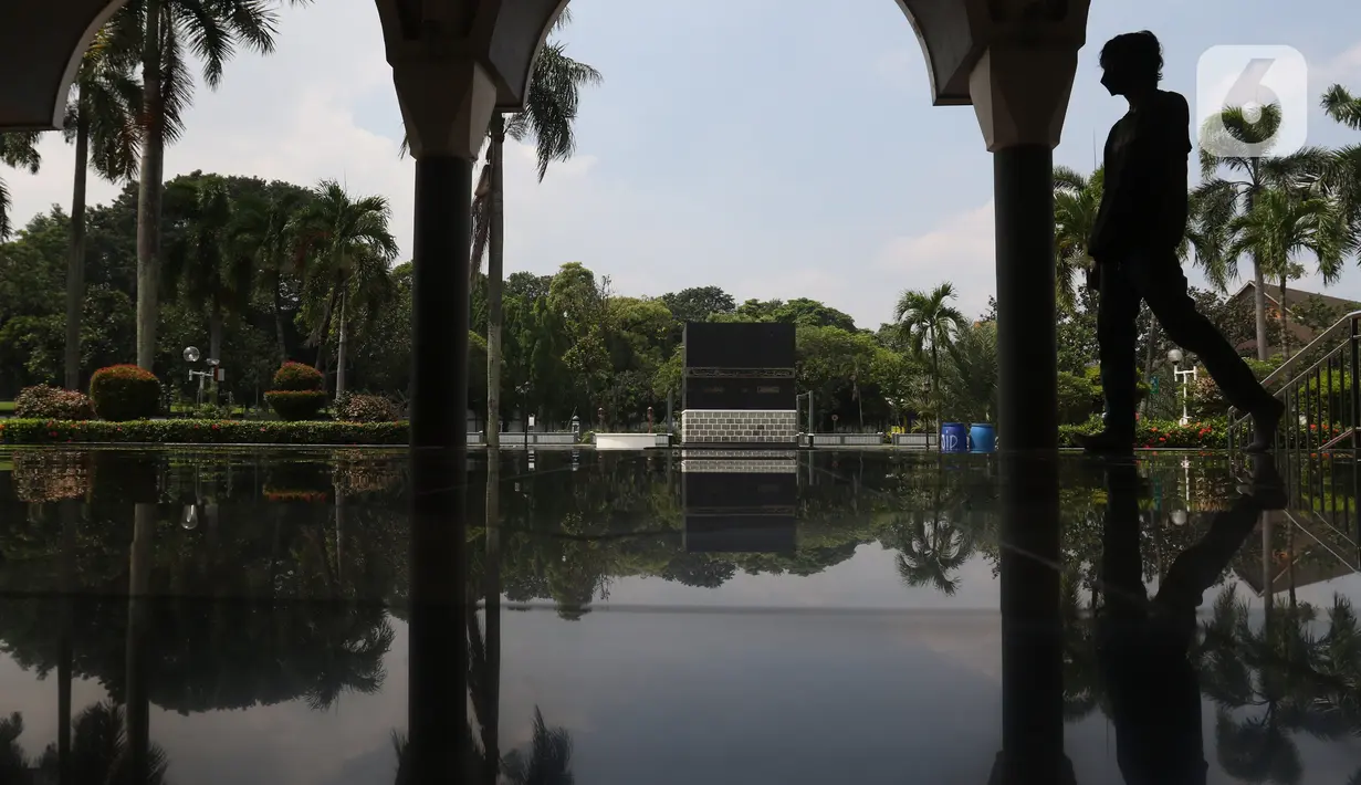Seseorang melintas dekat replika Kakbah di Asrama Haji Pondok Gede, Jakarta, Senin (23/5/2022). Asrama Haji Pondok Gede Jakarta siap melayani calon jemaah haji 1443 H/2022 M, yang dijadwalkan mulai masuk asrama pada 3 Juni 2022 mendatang sebelum keberangkatan menuju Tanah Suci Mekkah dan Madinah di Arab Saudi. (Liputan6.com/Herman Zakharia)