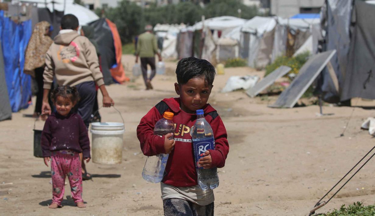Situasi ini menempatkan warga Palestina di Gaza, terutama anak-anak, pada risiko tinggi penyakit menular akibat keterbatasan air bersih dan sanitasi yang buruk. Tampak dalam foto, anak-anak mengambil air minum di kamp pengungsi Bureij, Jalur Gaza Tengah pada 28 April 2026. (Eyad Baba/AFP)