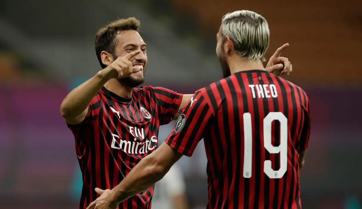 Gelandang AC Milan, Hakan Çalhanoğlu (kiri) berselebrasi dengan rekannya Theo Hernandez usai mencetak gol ke gawang Bologna pada pertandingan lanjutan Liga Serie A Italia di stadion San Siro di Milan, Italia, Sabtu, (18/7/2020). AC Milan menang telak 5-1 atas Bologna. (AP Photo/Luca Bruno)