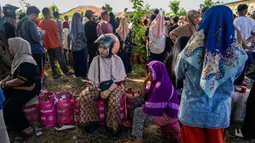 Kelangkaan gas di Kota Banda Aceh memicu kritik tajam dari berbagai pihak. Tampak dalam foto, warga menunggu untuk membeli tabung gas di sebuah stasiun pengisian dan pembelian LPG setelah banjir bandang di Banda Aceh pada Rabu 17 Desember 2025. (CHAIDEER MAHYUDDIN/AFP)