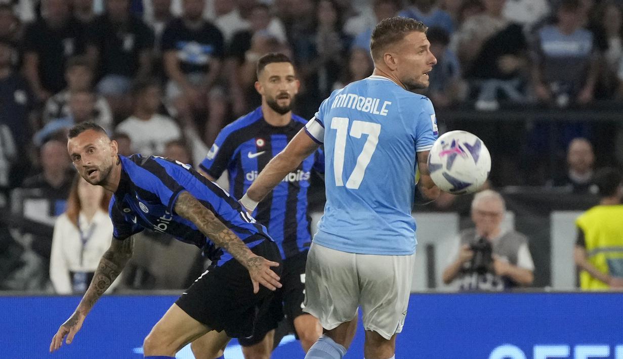 Gelandang Inter Milan, Marcelo Brozovic meninggalkan duel memperebutkan bola dengan penyerang Lazio Ciro Immobile pada pekan ketiga Serie A 2022/2023 di Stadio Olimpico, Roma, Sabtu (27/8/2022) dini hari WIB. Lazio mampu memberikan kekalahan perdana untuk Inter Milan usai menang 3-1. (AP Photo/Gregorio Borgia)