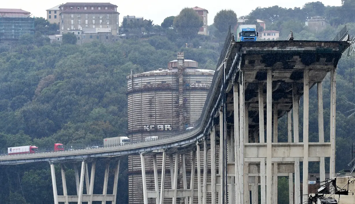 Sebuah truk berada di atas jembatan Morandi, dekat dengan bagian jalan layang yang runtuh, di Genoa, italia, Selasa (14/8). Jembatan ini merupakan penghubung penting antara Riviera Italia dengan pesisir selatan Perancis. (ANDREA LEONI/AFP)