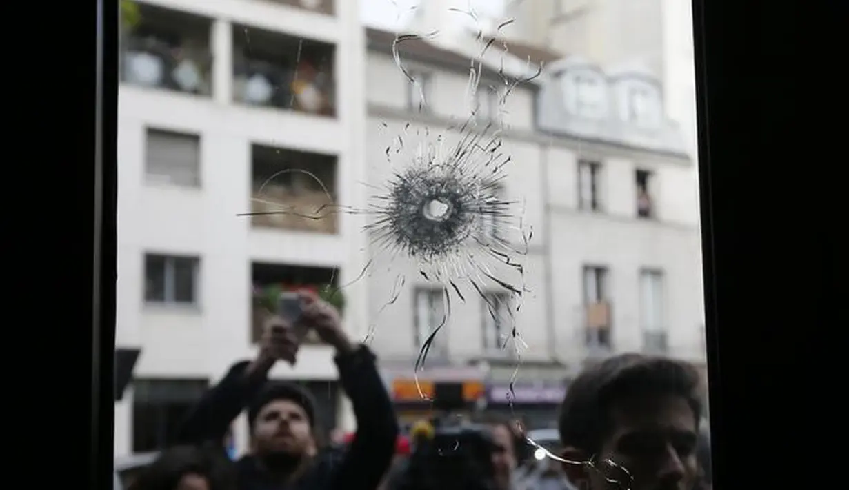Wartawan tampak mengabadikan gambar kaca disebuah restoran dimana penembakan terjadi di Paris, Prancis, Sabtu (14/11/2015). Dikabarkan ratusan orang tewas dalam serangan ini. (REUTERS/Gonzalo Fuentes)