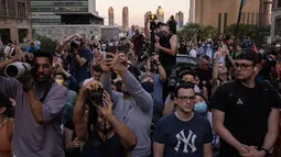 Orang-orang mengambil gambar saat matahari terbenam di Manhattan ketika fenomena "Manhattanhenge" di 42nd street, New York, Senin (11/7/2022). Dikenal dengan sebutan Manhattanhenge, fenomena terbenamnya matahari yang satu ini selalu membuat jalanan Manhattan macet. (Yuki IWAMURA / AFP)