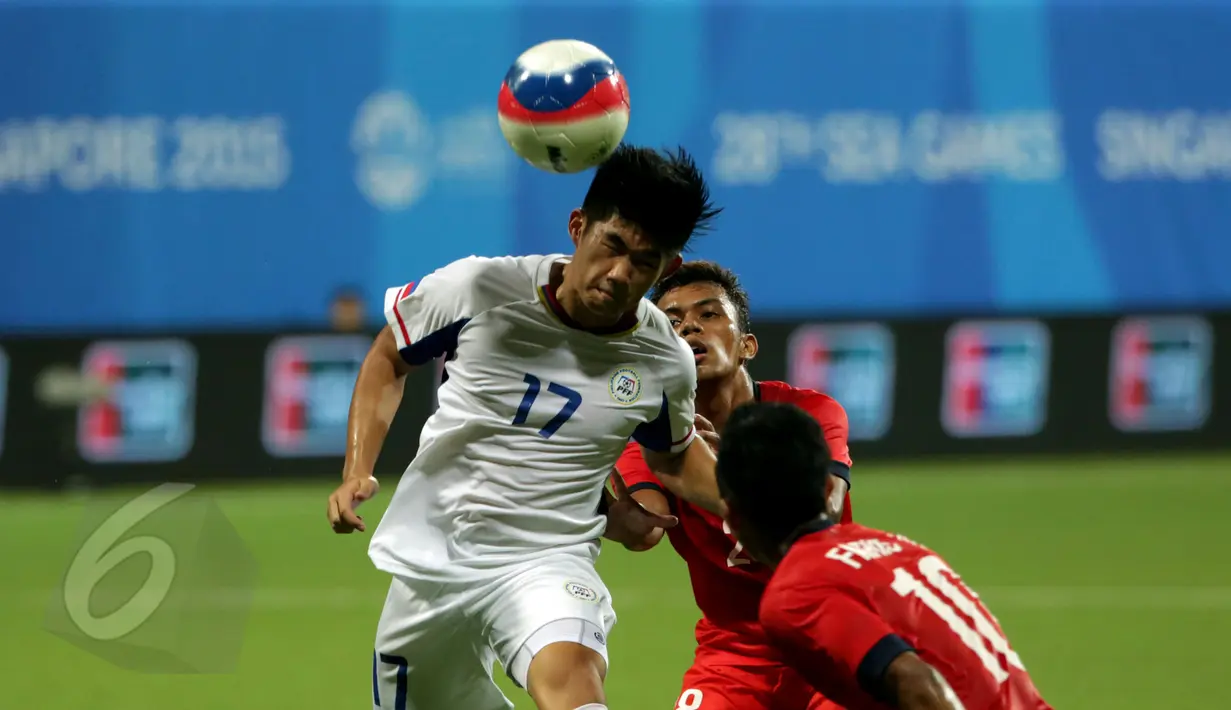 Gelandang timnas Filipina U-23, J Vicenzo Cheng (kiri) berjibaku berebut bola dengan dua pemain Singapura dalam laga grup A Sea Games 2015 di Stadion Jalan Besar, Singapura, Senin (1/6/2015). Singapura unggul 1-0. (Liputan 6.com/Helmi Fithriansyah)