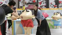 Seorang pengunjung berpose mengikuti ekspresi model Crayon Shinchan saat berfoto di pameran Joy City, Beijing (5/5/2015). Lima puluh model karakter kartun Jepang dalam berbagai pose dan ekspresi dihadirkan dipameran tersebut. (REUTERS/Jason Lee)