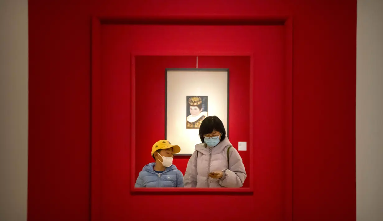 Seorang wanita dan anak mengenakan masker berjalan melalui galeri di Museum Seni Nasional China di Beijing, Rabu (1/2/2023). Pengunjung terus berduyun-duyun ke museum, situs bersejarah, dan tempat wisata di ibu kota China saat periode liburan Tahun Baru Imlek berakhir. (AP Photo/Mark Schiefelbein)