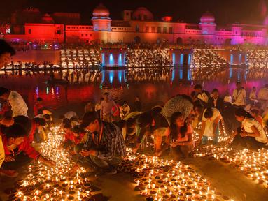 Masyarakat India menyalakan lampu dari tanah liat pada festival Diwali di tepi Sungai Sarayu, Ayodhya, Selasa (6/11). Kota di utara India itu memecahkan rekor dunia Guinness setelah menyalakan 300.150 lampu selama 45 menit. (AP/Rajesh Kumar Singh)