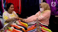 Calon pembeli menjajal pakaian impor bekas di Pasar Senen, Jakarta, Kamis (9/3/2023). Larangan impor baju bekas tercantum dalam Peraturan Menteri Perdagangan (Permendag) No.18/2021 tentang Barang Dilarang Ekspor dan Barang Dilarang Impor. (Liputan6.com/Faizal Fanani)