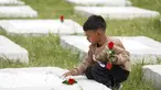 Seorang anak laki-laki meletakkan bunga di atas kuburan di pemakaman di desa Kato Tritos di pulau Lesbos, Laut Aegea timur laut, Yunani, Rabu (17/4/2024). (AP Photo/Panagiotis Balaskas)