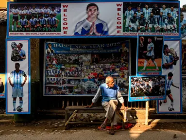 Seorang pria duduk di dekat kedai teh yang dihiasi poster timnas Argentina, di Ichhapur sekitar 35 km sebelah utara Kolkata pada 12 Desember 2022. Argentina berhasil lolos ke babak semifinal Piala Dunia 2022 Qatar yang akan melawan Kroasia. (AFP/Dibyangshu Sarkar)