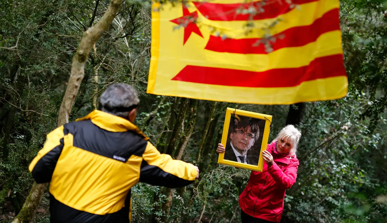 Seorang wanita memegang foto presiden terguling Catalonia, Carles Puigdemont saat mereka membawa ke Gunung Montserrat, Spanyol (28/4). Monserrat sendiri merupakan salah satu tempat ziarah bagi‎ umat Katolik yang paling dikenal di Eropa .(AFP/Pau Barrena)