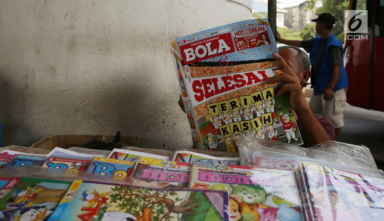 Pedagang membaca tabloid Bola di Terminal Kampung Melayu, Jakarta, Jumat (26/10). Hari ini menjadi terakhir tabloid Bola terbit. (Merdeka.com/Imam Buhori)