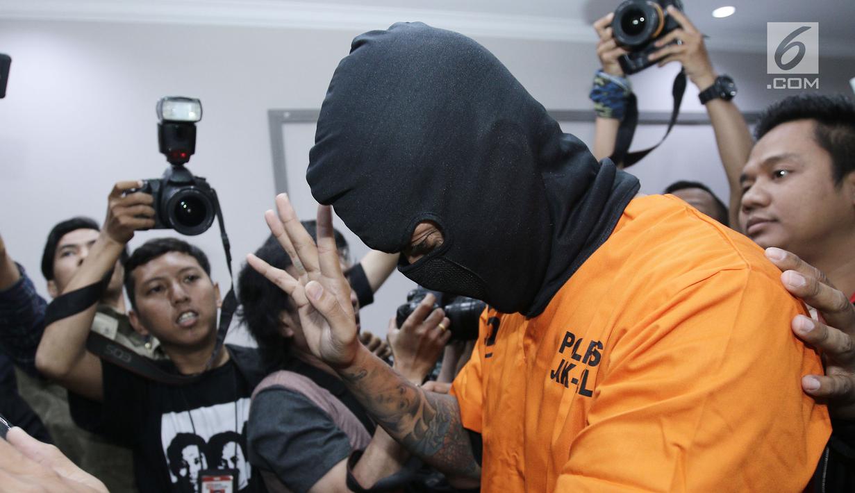 Aktor Tora Sudiro (kenakan penutup wajah hitam) saat dihadirkan dalam jumpa pers kepemilikan psikotropika di Mapolres Jakarta Selatan, Jumat (04/08). Tora dijerat dengan UU Psikotropika tahun 1997 pasal 62. (Liputan6.com/Herman Zakharia)