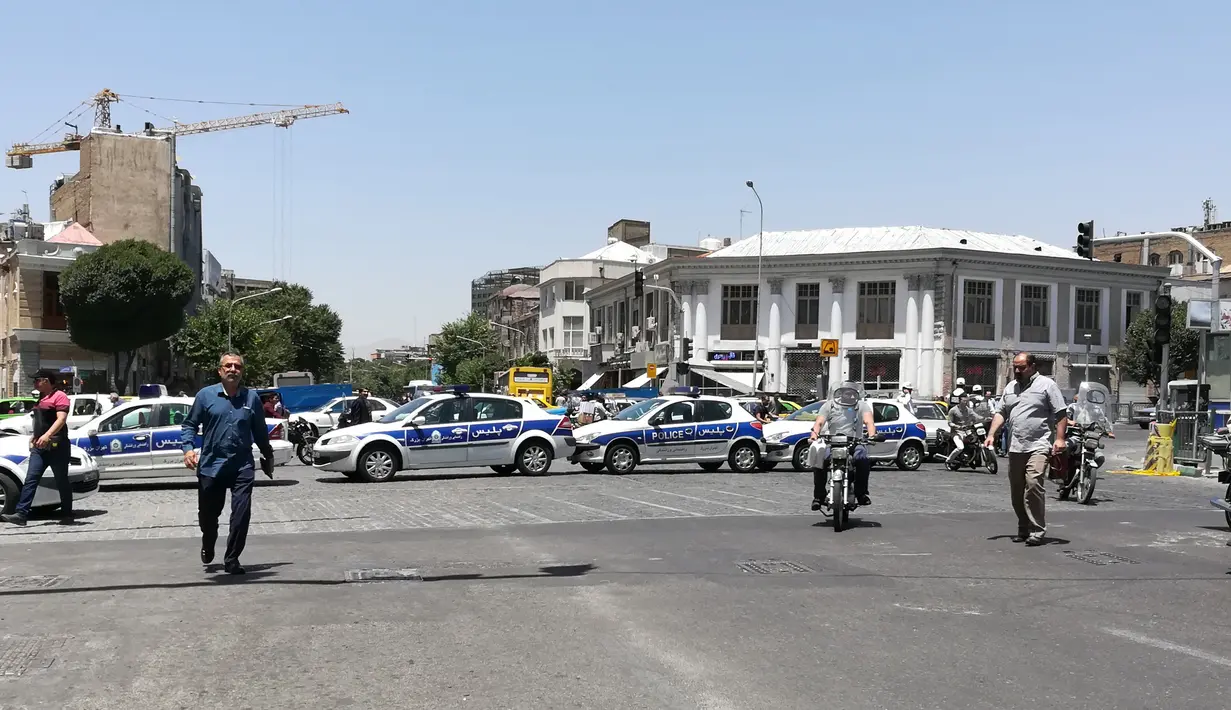 Sejumlah mobil polisi berdatangan usai terjadi penyerangan bersenjata di parlemen Iran,  Rabu (7/6). Tiga pria bersenjata dilaporkan melakukan penyerangan di dalam gedung parlemen Iran dengan menggunakan senjata api. (AFP/ATTA KENARE)
