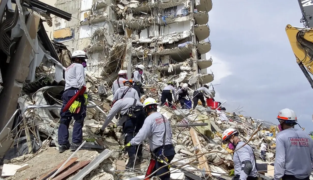 Petugas pencarian dan penyelamatan mencari korban melalui puing-puing di Champlain Towers South Condo, Surfside, Miami, Florida, Amerika Serikat, Jumat (25/6/2021). Puluhan orang telah dievakuasi dari reruntuhan bangunan. (Miami-Dade Fire Rescue via AP)