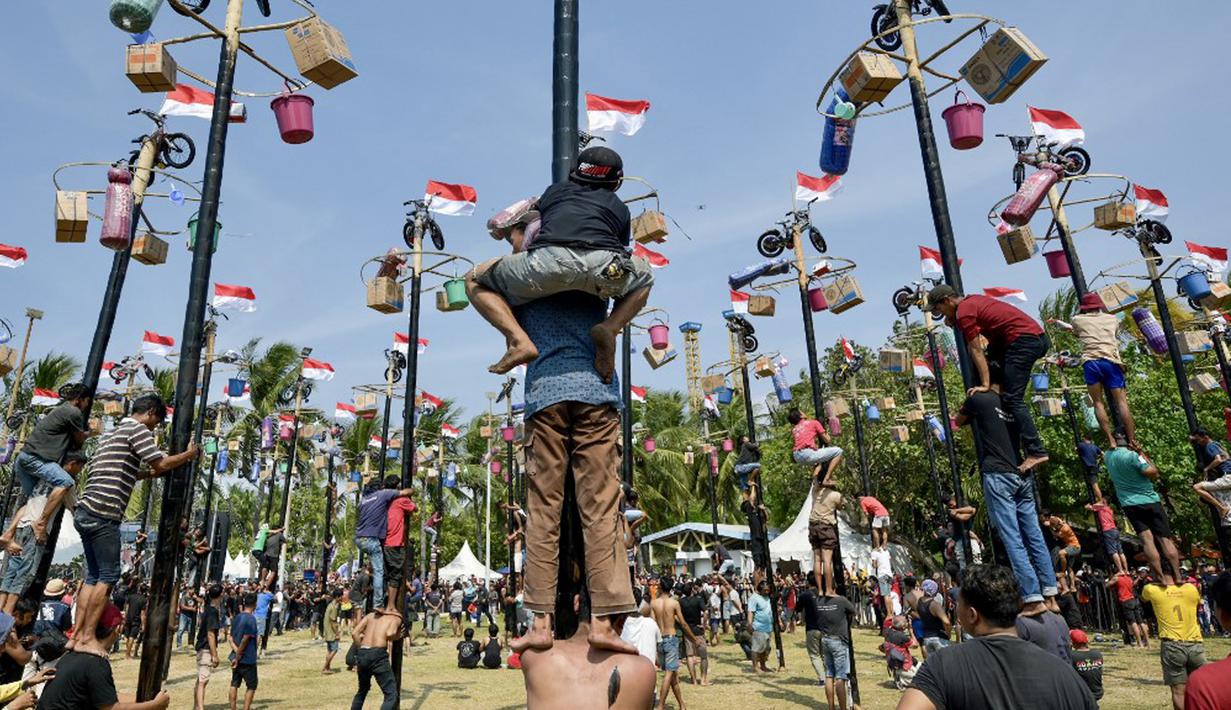Para peserta berusaha memanjat tiang-tiang berminyak untuk mengumpulkan hadiah di puncak saat perayaan Hari Ulang Tahun (HUT) ke-78 Republik Indonesia (RI) di Jakarta, Kamis (17/8/2023). (BAY ISMOYO/AFP)