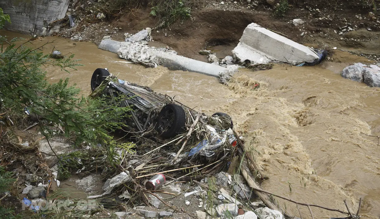 Sebuah mobil tergeletak di sungai setelah hujan lebat di Thessaloniki, Yunani utara, Sabtu, 17 Juni 2023. Rumah-rumah terendam banjir dan pohon-pohon tumbang serta mobil-mobil hanyut setelah hujan lebat di banyak pinggiran kota di bagian utara. (AP Photo/Giannis Papanikos)