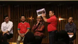 Gaya Sarman El Hakim yang menunjukan foto-foto dirinya saat berkunjung ke kantor pusat FIFA pada acara debat di  SCTV Tower, Senayan City, Jakarta, Selasa (04/10/2016). (Bola.com/Nicklas Hanoatubun)