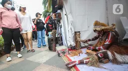 Warga melihat Suku dari Papua sedang mematung saat mengkampanyekan Sail Teluk Cenderawasih bertepatan dengan Hari Bebas Kendaraan Bermotor (HBKB), Kawasan Thamrin, Jakarta, Minggu (8/10/2023). (Liputan6.com/Angga Yuniar)