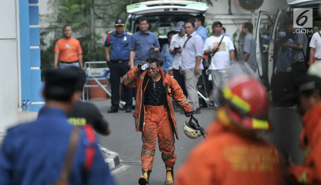 Petugas pemadam membasuh muka dengan air usai melakukan pendinginan di lokasi kebakaran Gedung Kemenhub, Jakarta, Minggu (8/7). Sampai saat ini Sudin Pemadam Kebakaran Jakpus  mencatat ada 20 korban selamat dalam kebakaran. (Merdeka.com/Iqbal S Nugroho)