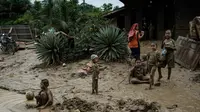 Kondisi lingkungan dan sanitasi yang kurang memadai pasca- bencana dapat memicu peningkatan kasus Infeksi Saluran Pernapasan Akut (ISPA), seperti batuk, pilek, hingga demam. Tampak dalam foto, anak-anak bermain di genangan lumpur di Pengidam, Aceh Tamiang, pada Senin 15 Desember 2025. (Yasuyoshi Chiba/AFP)