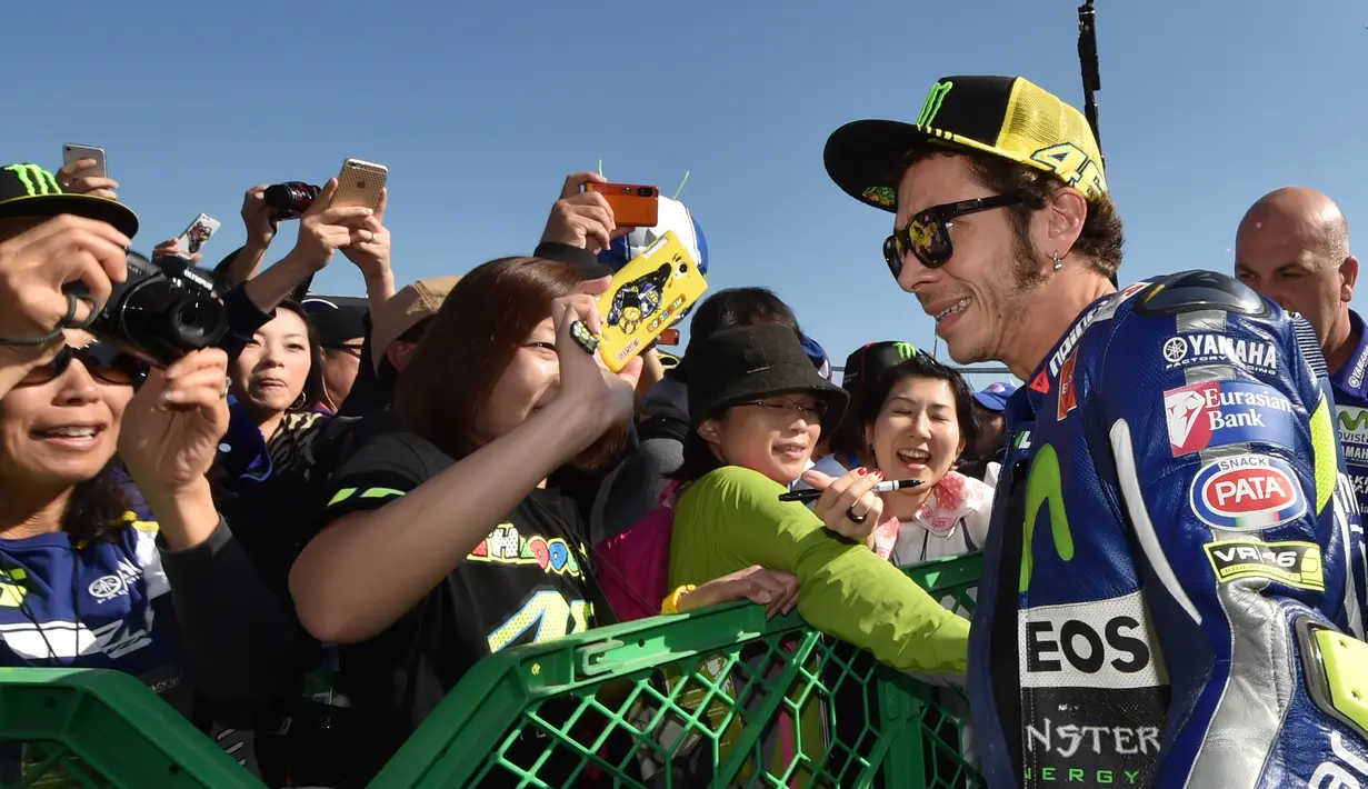Valentino Rossi dikelilingi penggemarnya di paddock sebelum latihan bebas GP Jepang di Sirkuit Motegi, Jepang, (9/10/2015). (AFP Photo/Kazuhiro Nogi)