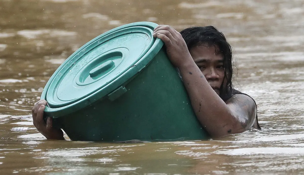 Warga menggunakan wadah plastik sebagai pelampung saat menerobos air banjir di Marikina, Filipina akibat Topan Vamco pada  12 November 2020. Topan Vamco menghantam Filipina dan menyebabkan sungai meluap sehingga membanjiri daerah dataran rendah di timur laut Filipina. (AP Photo/ Aaron Favila)
