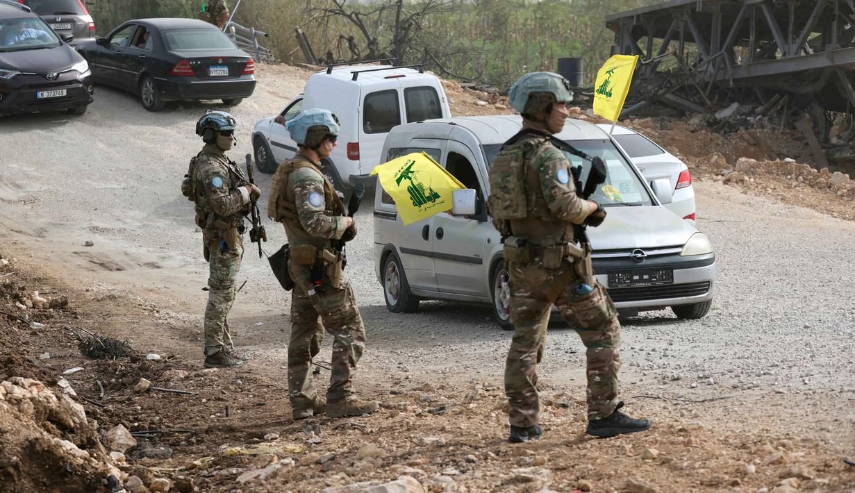 Ribuan warga yang mengungsi mulai kembali ke rumah mereka, terutama yang tinggal di wilayah Lebanon selatan dan pinggiran Beirut. Tampak dalam foto, Kontingen Prancis dari Pasukan Sementara Perserikatan Bangsa-Bangsa di Lebanon (UNIFIL) berpatroli di daerah tersebut sementara warga yang mengungsi sambil mengibarkan bendera Hizbullah kembali ke rumah mereka melalui jalan darurat yang dibangun di lokasi jembatan Qasmieh yang hancur akibat serangan Israel, di wilayah Al-Qasmiyeh, Lebanon Selatan, pada Sabtu 18 April 2026. (MAHMOUD ZAYYAT/AFP)