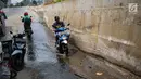 Pengendara melintasi genangan air dekat tanggul pengaman pantai yang bocor di Muara Baru, Jakarta, Selasa (11/12). Tanggul pengaman pantai untuk mencegah banjir rob tersebut bocor karena tingginya volume pasang surut air laut. (Liputan6.com/Faizal Fanani)