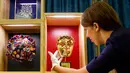 <p>Petugas menunjukkan Penghargaan Kehormatan BAFTA yang diberikan kepada aktor Kenneth Branagh dan Ratu Elizabeth II pada bulan April 2013 jelang pameran Hadiah Kerajaan di Istana Buckingham, London (20/07). (AFP PHOTO / Tolga Akmen)</p>