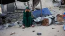 Seorang perempuan bereaksi sambil duduk di samping peralatan makannya yang diselamatkan dari reruntuhan rumah yang hancur akibat serangan Israel di Khan Younis, Jalur Gaza selatan, pada Rabu 29 Oktober 2025. Kesepakatan gencatan senjata yang dimotori Amerika Serikat dan mulai berlaku pada 10 Oktober lalu terancam gagal, kedua pihak bertikai baik Israel maupun Hamas sama-sama saling menuduh satu sama lain melanggar. (BASHAR TALEB/AFP)
