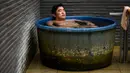 Masazumi Kato bersantai dalam bak mandi di pemandian air panas Jepang atau onsen di Yokohama, prefektur Kanagawa pada 29 Mei 2020. Dengan pencabutan status darurat nasional pada Senin (25/5) lalu, banyak bisnis yang mulai beroperasi kembali tak terkecuali dengan onsen. (Behrouz MEHRI/AFP)