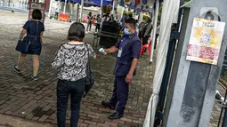 Petugas mengecek suhu tubuh jemaat saat misa Minggu Paskah di Gereja Katedral, Jakarta, Minggu (4/4/2021). Sejumlah personel gabungan TNI-Polri disipakan untuk melakukan pengamanan di sejumlah gereja pada perayaan Paskah. (Liputan6.com/Faizal Fanani)