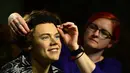 Seorang pegawai tampak merapikan patung salah satu member One Direction, Harry Styles, di museum lilin Madame Tussauds, London, Rabu (6/8/14). (AFP PHOTO/Carl COURT)