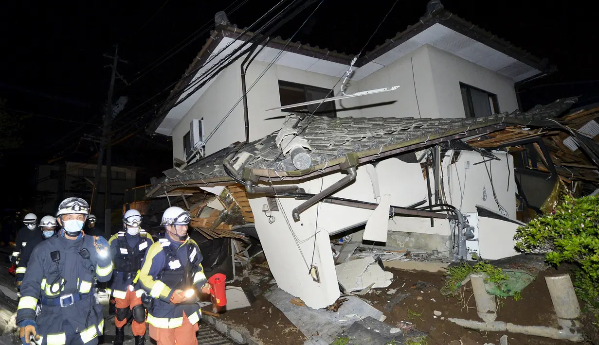 Petugas pemadam kebakaran memeriksa sebuah rumah yang runtuh setelah gempa bumi di kota Mashiki, Prefektur Kumamoto, Jepang selatan , Jumat (15/4). Gempa berkekuatan 6,4 SR itu menewaskan sembilan orang dan 760 lainnya terluka. (REUTERS/Kyodo)