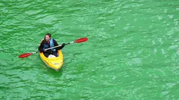 Sebuah perahu kayak melintasi Sungai Chicago yang berubah hijau pada peringatan hari Santo Patrick di Illinois, Sabtu (17/3). Hari raya Santo Patrick diperingati setiap tanggal 17 Maret yang diidentikkan dengan warna hijau. (Scott Olson/Getty Images/AFP)